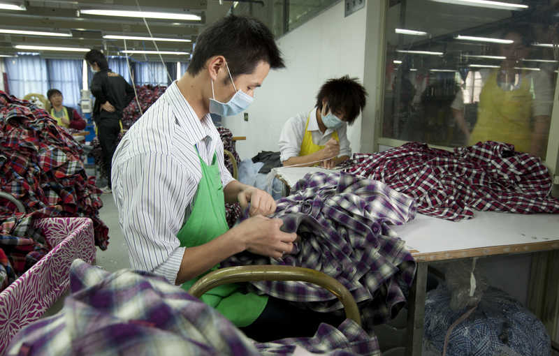 Workers process shirts at Lever Style Inc. factory in Shenzhen