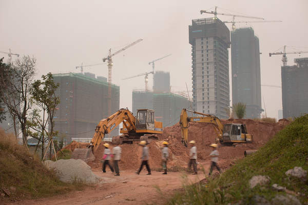 Workers walk past construction equipment in Pazhou, Haizhu District