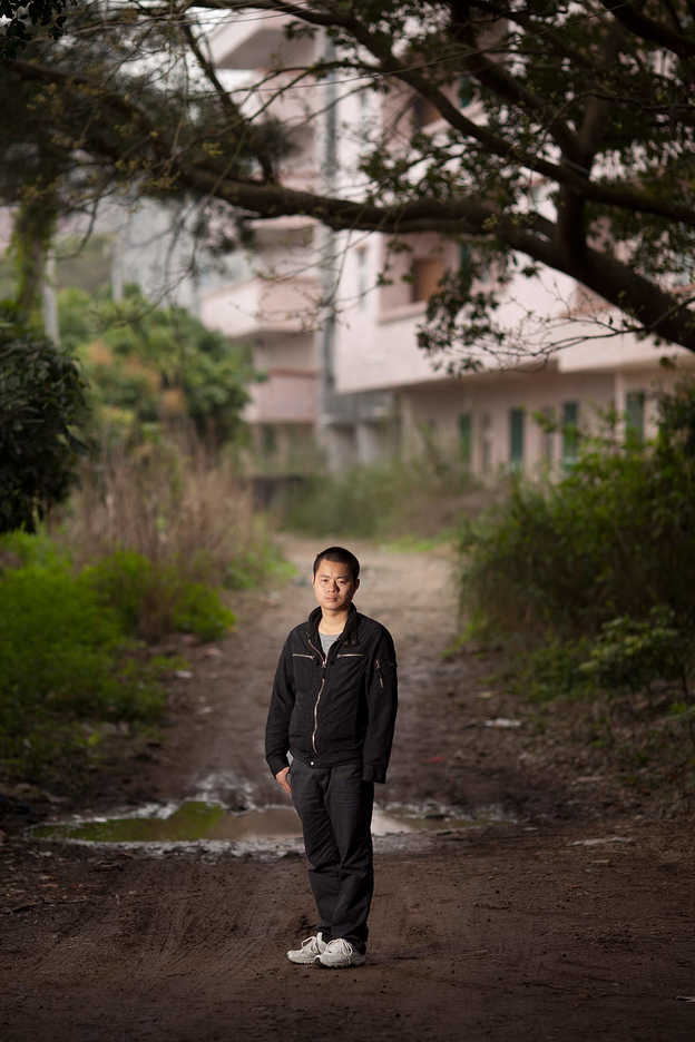 Zhan Dexin poses near his missing son's school in Huizhou, Guangdong Province, China