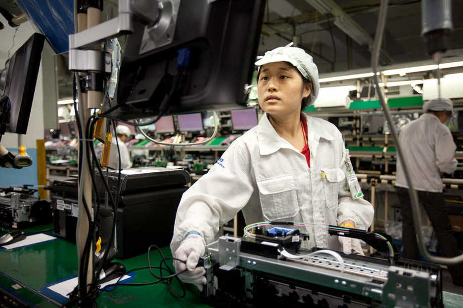 A Foxconn worker tests a computer printer along the assembly line in Shenzhen
